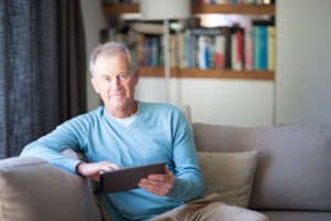 Senior man using tablet computer at home